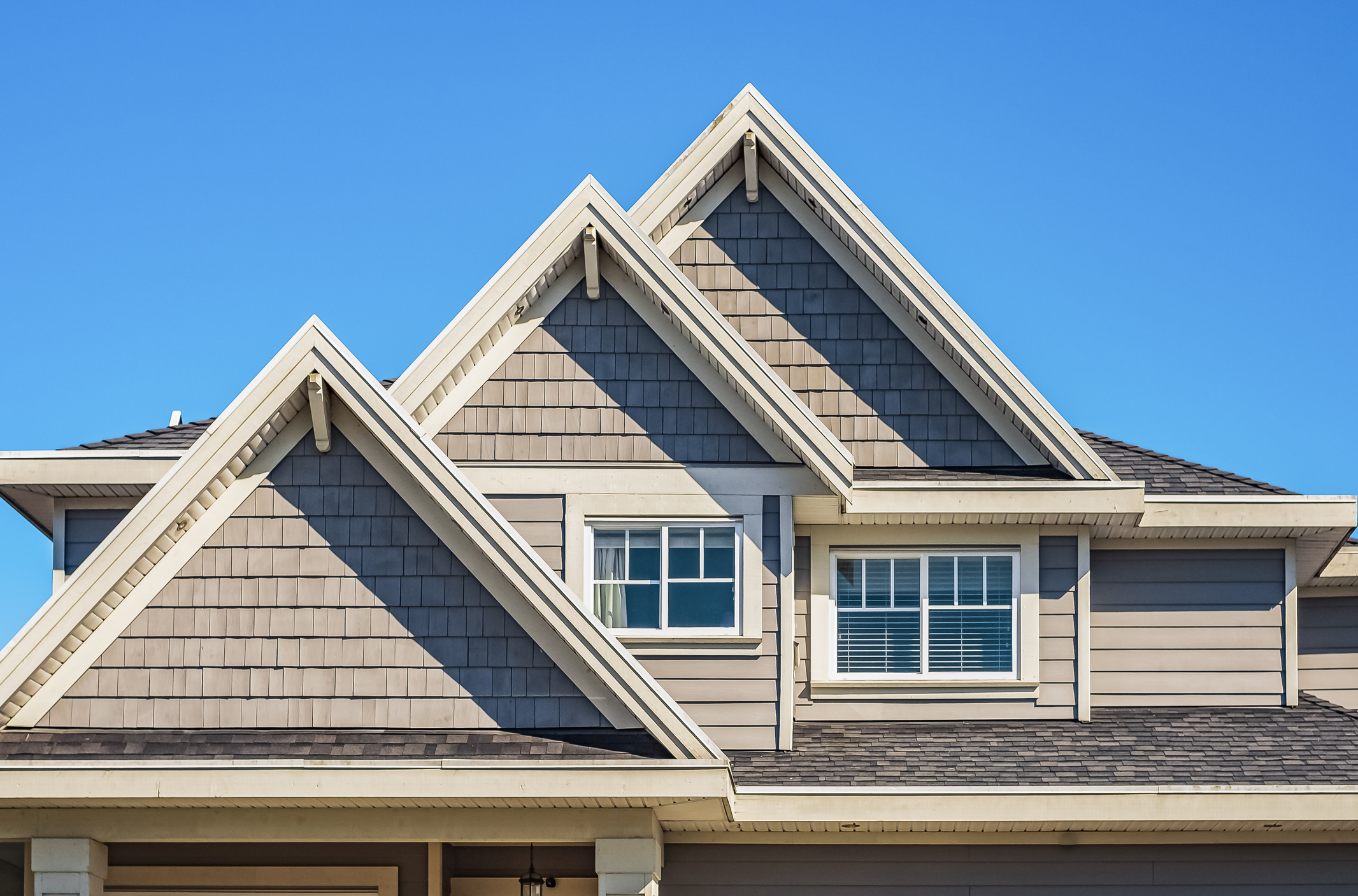 residential gable roof exterior showing ventilation structure and roof design under clear blue sky