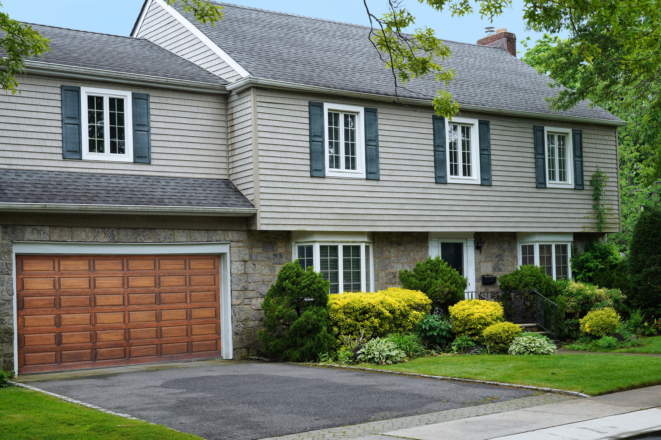 suburban house exterior with horizontal siding stone foundation garage and landscaped front yard