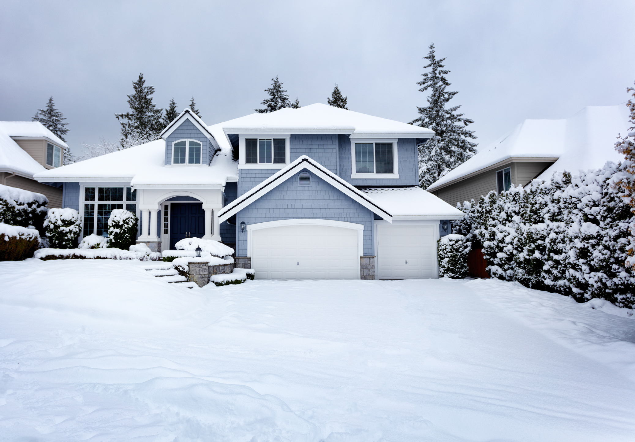 Large suburban home covered in snow after a winter storm in a residential neighborhood