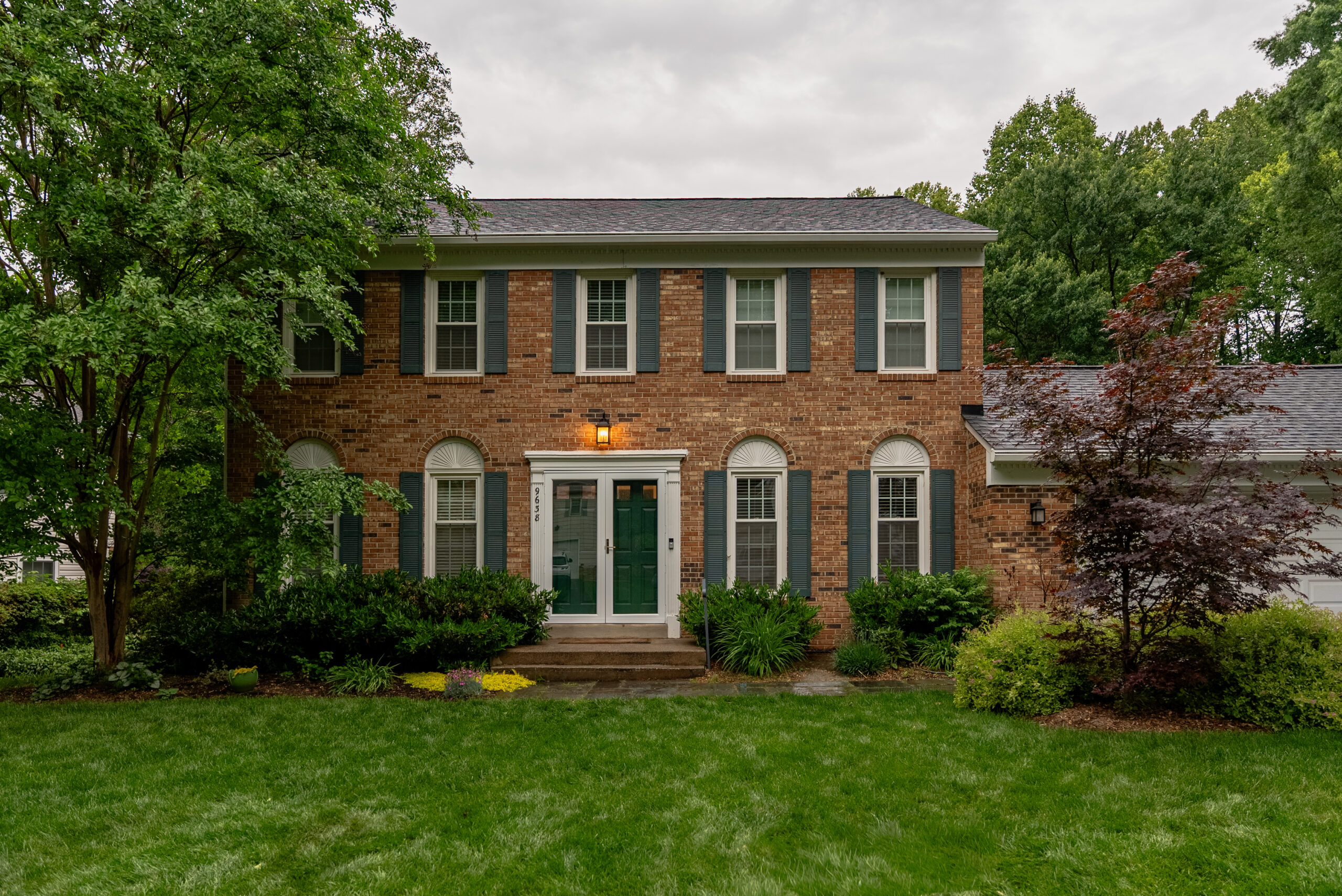 Full front elevation of a brick colonial home with a green double-door entry in Fairfax, VA